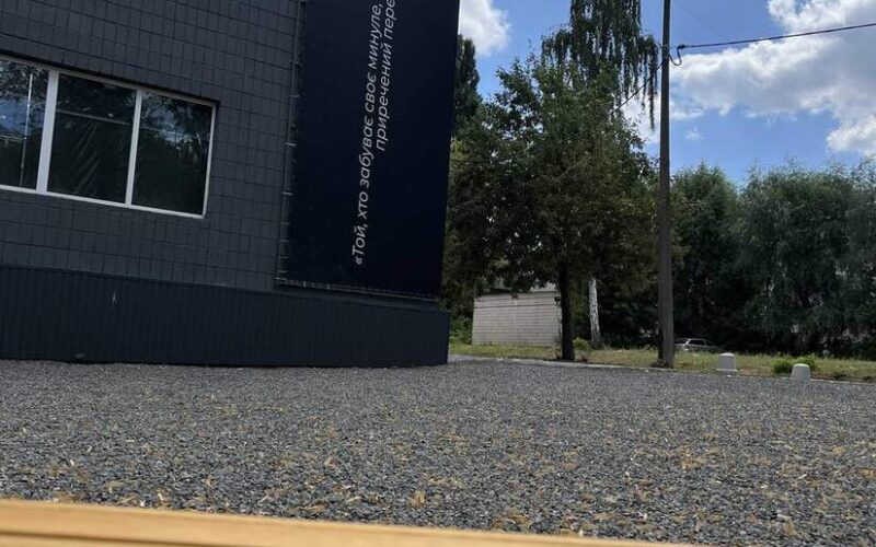 Будівля заповідника з банером-цитатою, на передньому плані дерев’яна лава