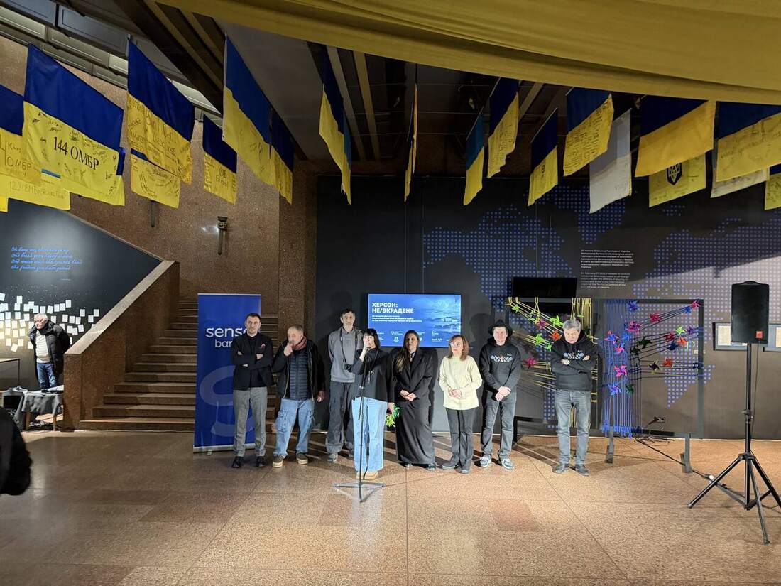 Відкриття виставки: куратори та учасники стоять перед глядачами на тлі екрана з назвою проєкту